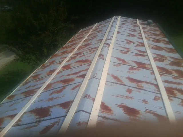 Rusted metal roof panels with new wood purlins before replacement — Storm Damage Roof Repair in Briggsdale by Roofing Brothers