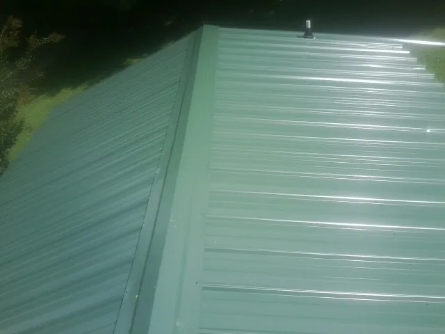 New green metal panels meeting at the ridge of a roof in Briggsdale
