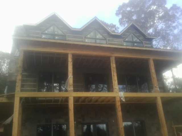 Dormers and porch framing on a large log home under construction — Roof Coating work by our crew in Briggsdale