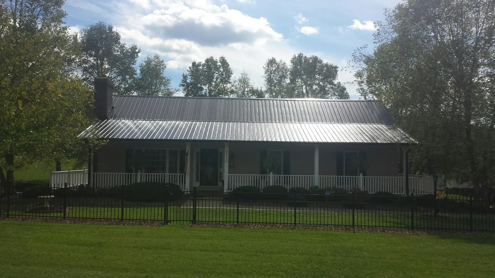 Gray metal roof on a brick ranch with a full width front porch — Gutter Guard Installation work by our crew in Briggsdale