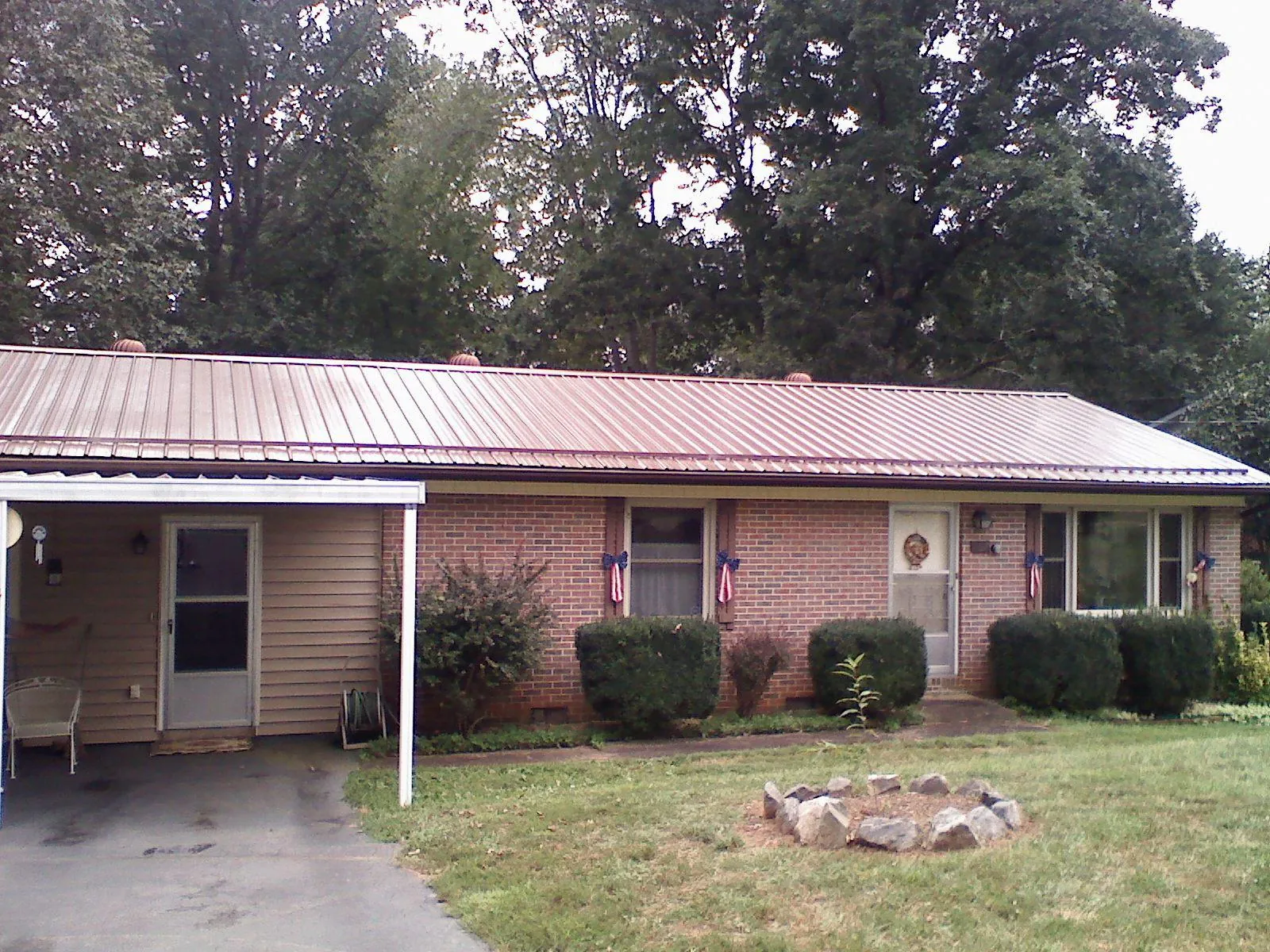 Bronze metal roof and carport on a brick ranch home — Roof Repair work by our crew in Briggsdale